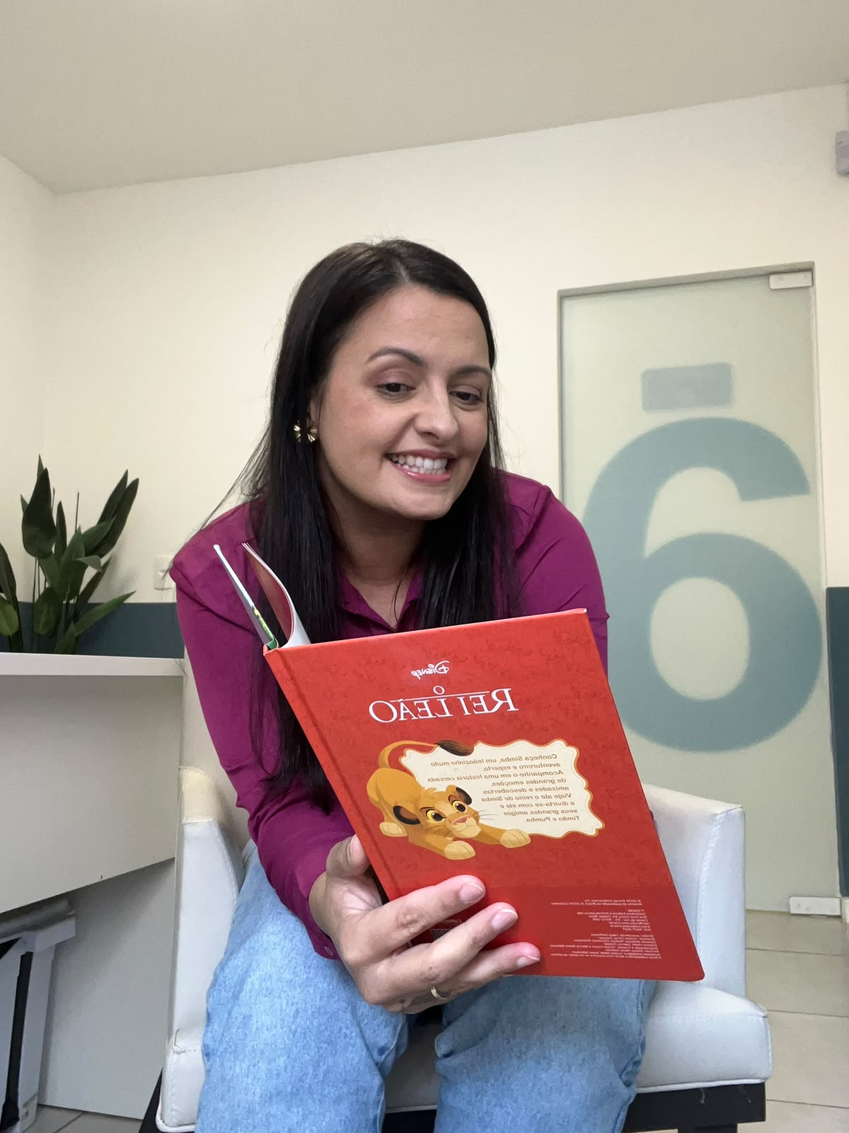 Adayle Weber sorrindo e segurando um livro infantil vermelho